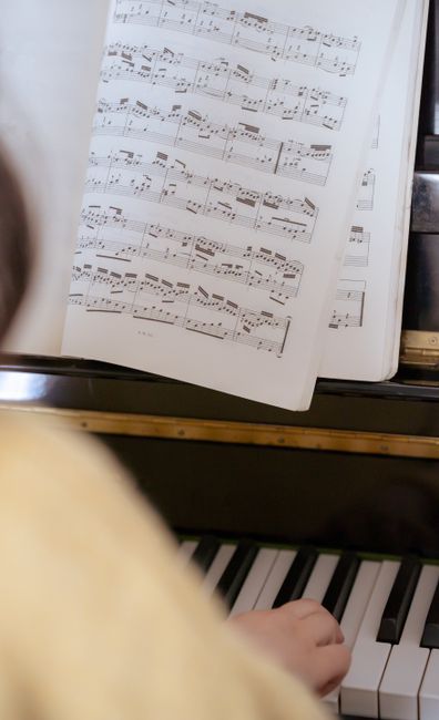 A close-up view of the interior of an upright piano with the top lid open, revealing the hammers, strings, and mechanical components in a black and white photograph. The piano's internal parts include multiple rows of hammers aligned with the strings, which are visible beneath the keys. The bottom portion shows the keyboard with black and white keys, some of which are slightly worn or discolored. The surrounding environment suggests an indoor setting with soft lighting, and the photo captures the detailed mechanisms involved in musical instrument movement and sound production. This image can support content related to packing, moving, or transporting musical instruments during home relocation or furniture transport processes, as provided by Man with Van Haringey.